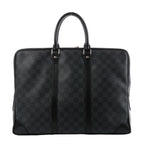 Louis Vuitton Porte Documents Voyage briefcase in dark gray Damier Graphite with black leather trim, two top handles, and zip-top closure on a white background.