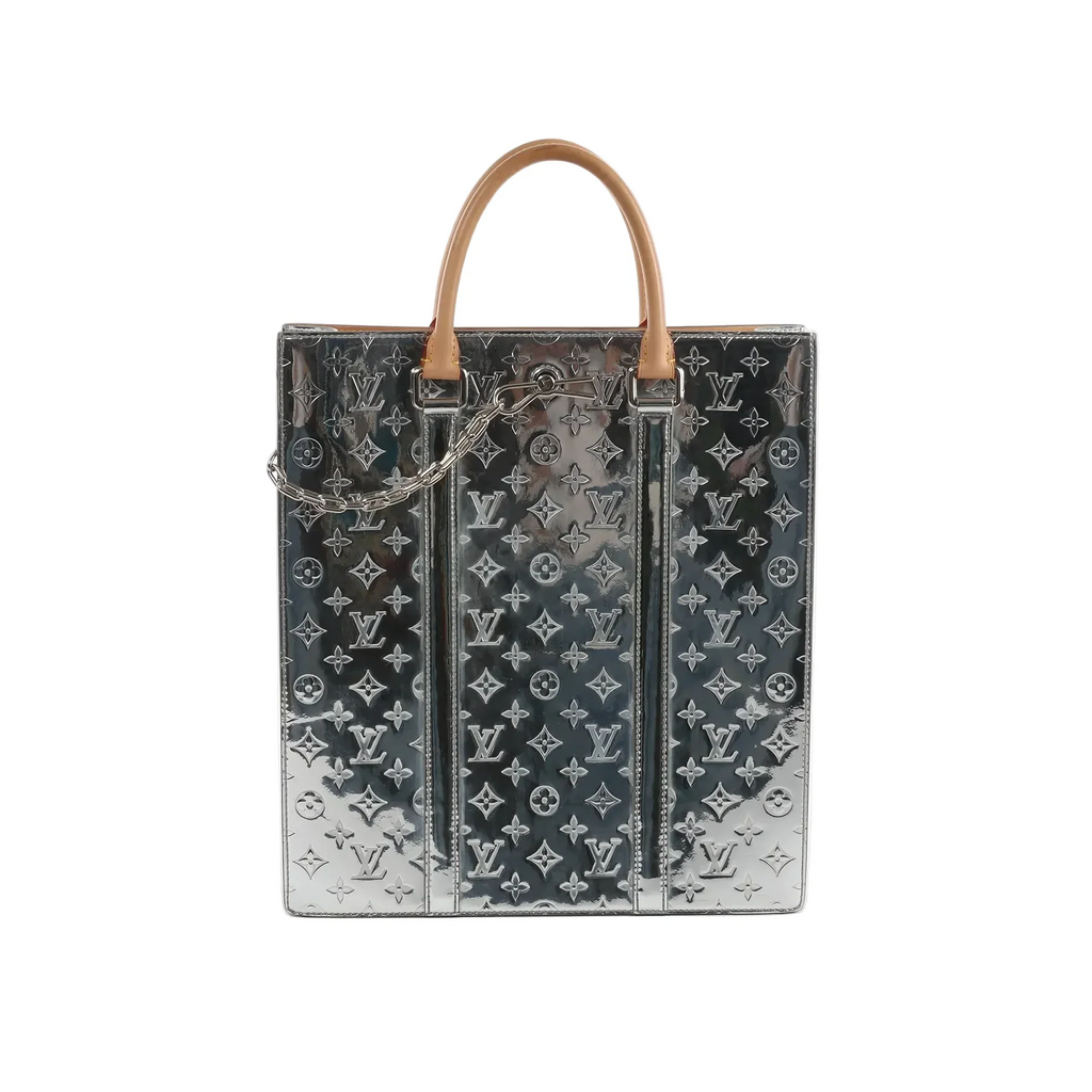 Louis Vuitton Sac Plat tote in reflective silver Monogram Mirror with tan top handles, embossed LV monogram pattern, and a silver chain detail on the front.