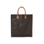 Front view of a tall brown Louis Vuitton Sac Plat Monogram canvas tote bag with two tan leather top handles on a white background.