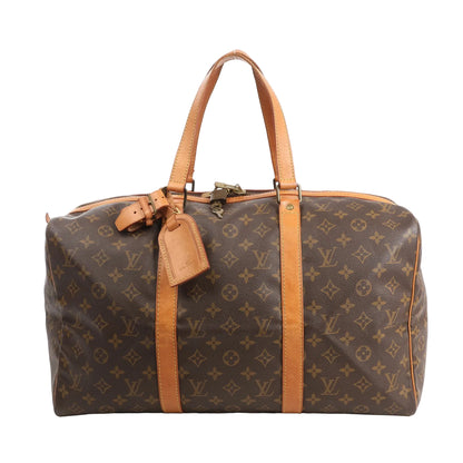 Front view of a Louis Vuitton Sac Souple 45 travel bag in brown Monogram canvas with natural leather trim, dual rolled handles, luggage tag, and gold-tone hardware.