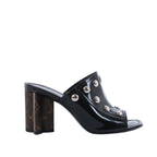 Pair of black Louis Vuitton patent leather mule sandals with open toes and silver-tone Monogram studs, photographed from the front.