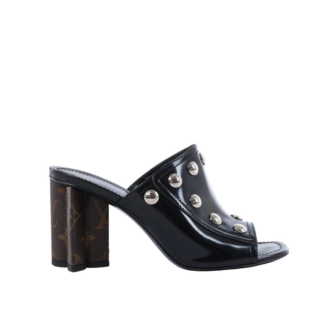 Pair of black Louis Vuitton patent leather mule sandals with open toes and silver-tone Monogram studs, photographed from the front.
