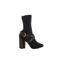 Side view of Louis Vuitton Silhouette black knit ankle boot with brown Monogram crossover straps, gold-tone buckle and Monogram-covered heel.