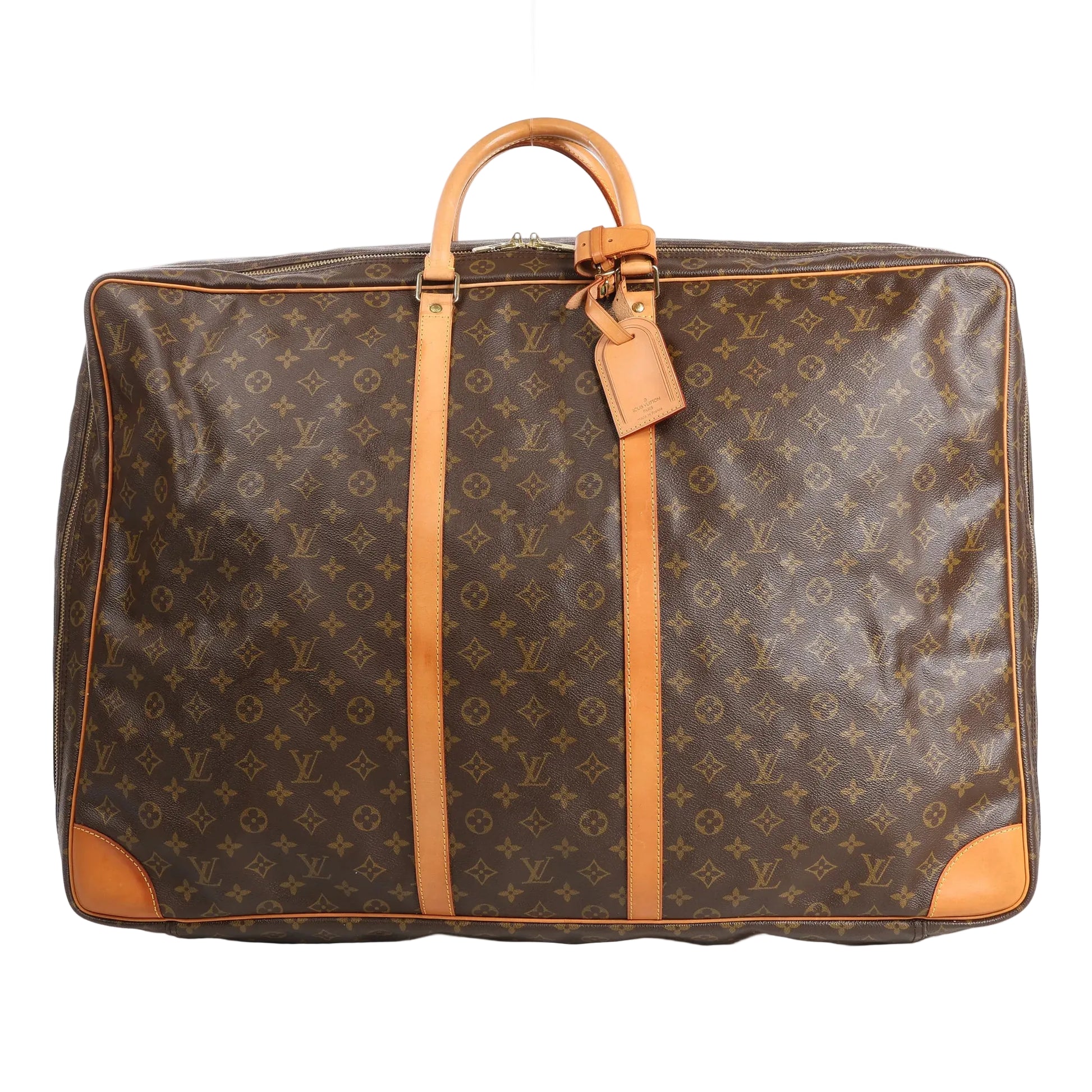 Louis Vuitton Sirius 65 travel bag in brown Monogram Canvas featuring natural Vachetta leather top handles, vertical leather trim, gold-tone hardware, and a large rectangular silhouette with rounded corners and luggage tag detail.