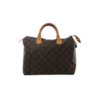 Front view of Louis Vuitton Speedy 30 handbag in brown Monogram canvas with vachetta leather top handles, zip-top closure, and hanging leather clochette with padlock.