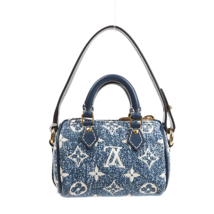 Front view of a Louis Vuitton Speedy Micro handbag in blue Monogram denim with white logo pattern, blue leather top handles, and a detachable shoulder strap.