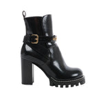Side view of a black Louis Vuitton Star Trail patent leather ankle boot with a high block heel, cleated platform and gold-tone buckled ankle strap.