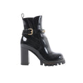 Black Louis Vuitton Star Trail Line patent leather ankle boot with gold buckle strap and monogram hardware, high block heel, and chunky lug platform sole, side view on white background