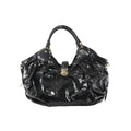 Front view of Louis Vuitton Surya XL bag in black patent Mahina leather with perforated Monogram pattern, ruched body, dual top handles with stud accents, and gold-tone clasp closure.