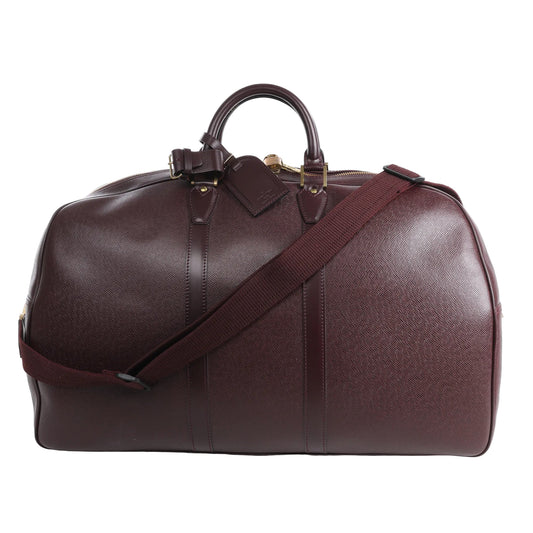 Louis Vuitton Taiga GM Kendall Travel Bag in burgundy leather with fine textured finish, top handles, detachable shoulder strap, gold-tone hardware, and structured duffel silhouette ideal for travel.