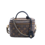 Brown Louis Vuitton Vanity NV PM Monogram bag with black leather top handle, gold-tone chain strap and zip closure.