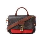 Front view of Louis Vuitton Vaugirard PM bag in brown Monogram canvas with red leather base, top handle, adjustable shoulder strap, and gold-tone padlock clasp.