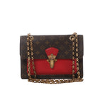 Louis Vuitton Victoire Monogram canvas crossbody bag with red leather front panel, gold-tone clasp and double chain shoulder strap.