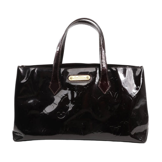 Louis Vuitton Wilshire PM handbag in burgundy Monogram Vernis patent leather with dual handles, gold-tone nameplate, and glossy finish, displayed on a white background.