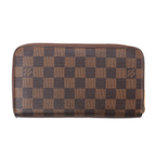 Louis Vuitton Zippy wallet in brown Damier Ebene coated canvas with checkerboard pattern and gold-tone zip-around closure on white background.