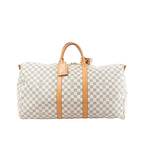 Louis Vuitton Damier Azur Keepall 55 travel bag with tan leather handles, vertical leather straps, luggage tag, and top zip on white background (shoulder strap not shown)
