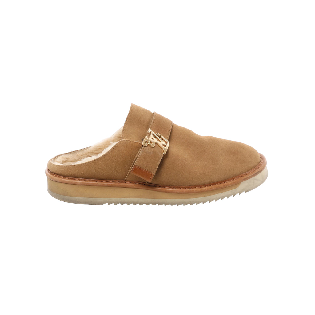 Side view of a Louis Vuitton brown suede mule with cream fleece lining, an open back, gold-tone LV hardware on the front strap and a thick cream sole.