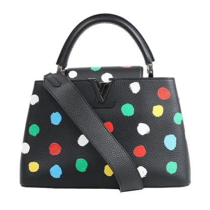 Louis Vuitton x Yayoi Kusama Capucines MM handbag in black Taurillon leather, adorned with colorful painted polka dots in white, green, red, blue, and yellow, featuring a top handle, wide shoulder strap, and black LV initials, displayed against a white background.