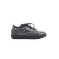 Maison Margiela x Reebok Club C black leather sneaker with black laces, stitched panel design, Reebok side logo, and black rubber sole, side view on white background