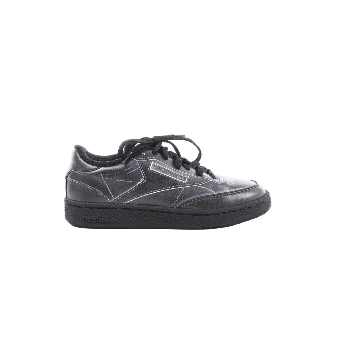 Maison Margiela x Reebok Club C black leather sneaker with black laces, stitched panel design, Reebok side logo, and black rubber sole, side view on white background
