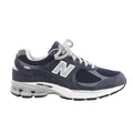 Side view of a navy New Balance sneaker with suede overlays, mesh panels, grey trim and laces, a silver-tone N logo and a white and grey sole.