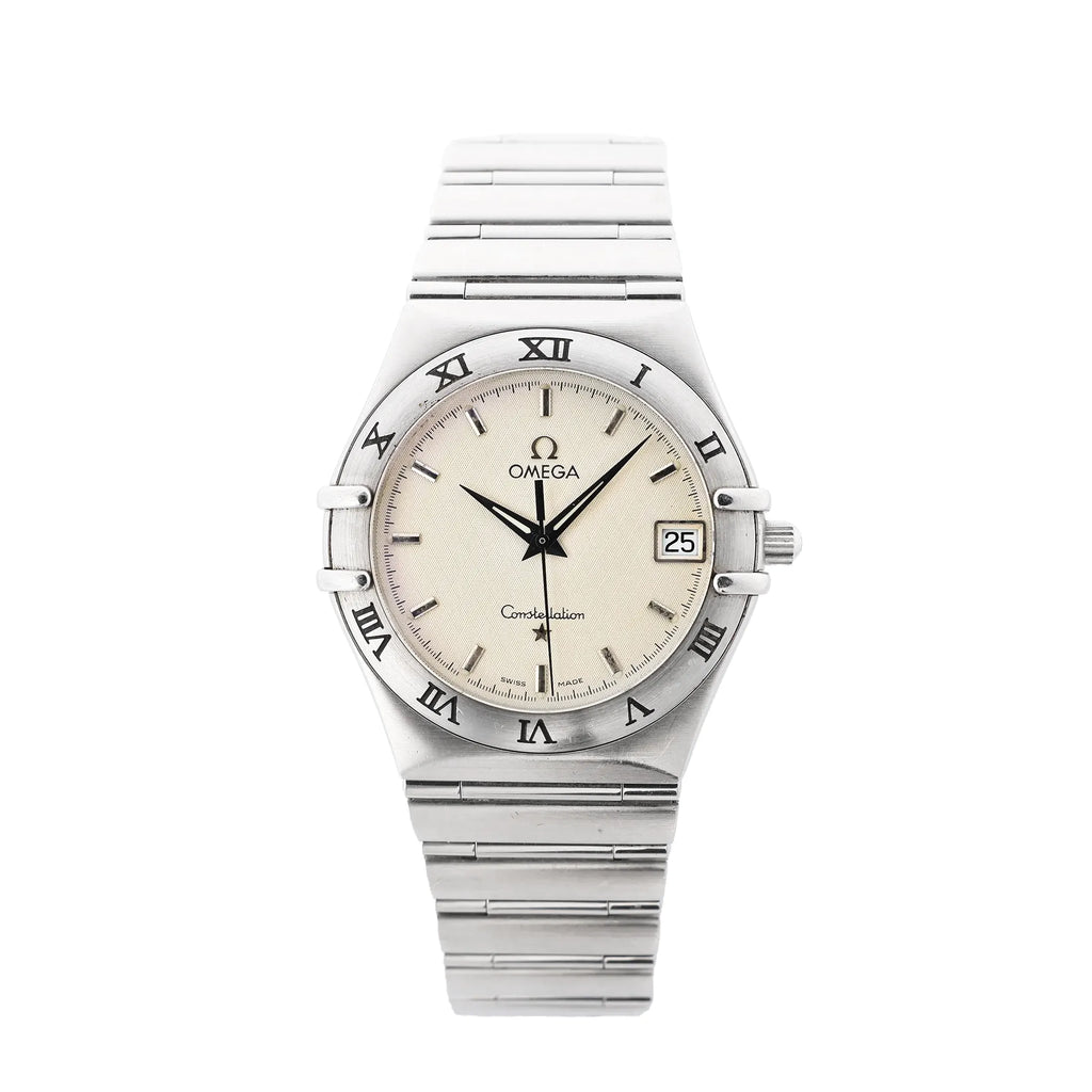 Omega Constellation stainless steel watch with champagne-beige dial, Roman numeral bezel, date window at 3 o’clock, baton hour markers, and stainless steel bracelet.