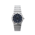 Omega Constellation stainless steel watch with navy blue dial, Roman numeral bezel, baton hour markers, black hands and integrated bracelet on white background.