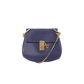 Chloé Drew navy blue pebbled leather crossbody bag with gold-tone lock closure and gold chain strap, front view on white background