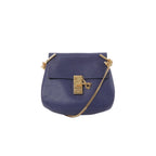 Chloé Drew navy blue pebbled leather crossbody bag with gold-tone lock closure and gold chain strap, front view on white background