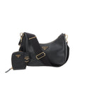 Prada Re-Edition 2005 black leather crossbody bag with gold-tone triangle logo, wide adjustable strap, and detachable mini zip pouch in front