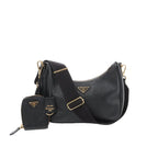 Prada Re-Edition 2005 black leather crossbody bag with gold-tone triangle logo, wide adjustable strap, and detachable mini zip pouch in front