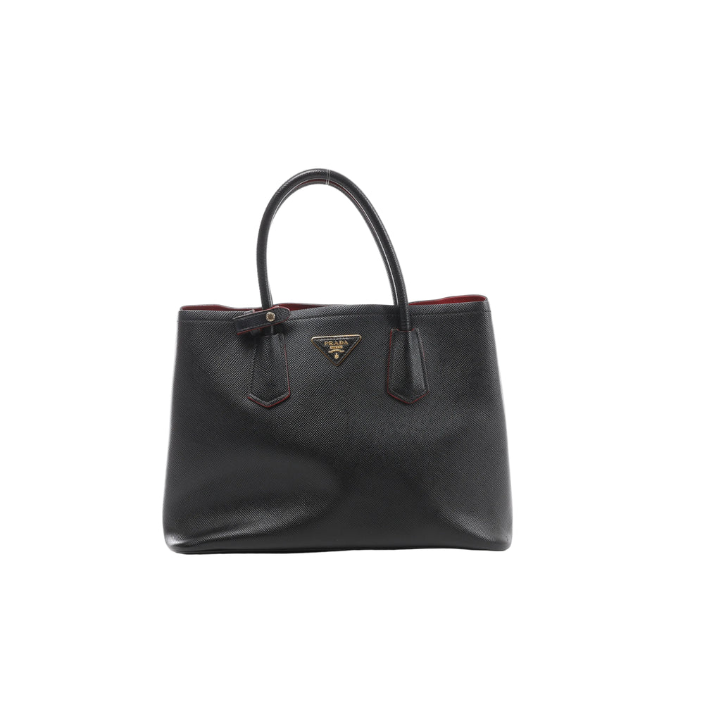 Front view of Prada Cuir black Saffiano leather handbag with twin rounded handles, red edging and a gold-tone triangular Prada logo.