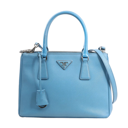 Prada Galleria handbag in blue Saffiano Lux leather with dual top handles, detachable shoulder strap, and silver-tone hardware featuring the iconic triangular logo plaque.