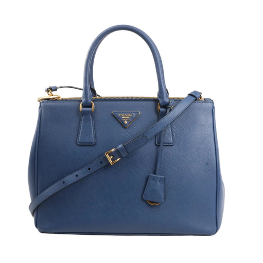 Prada Galleria 1BA274 2-way handbag in navy blue Saffiano Lux leather, featuring dual top handles, adjustable shoulder strap, gold-tone hardware, and the signature Prada triangle logo on the front.