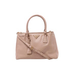Front view of a beige Prada Galleria Saffiano leather handbag with twin top handles, an adjustable shoulder strap and a gold-tone Prada triangle logo.