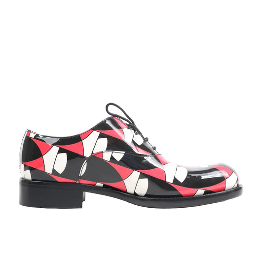 Side view of a multicolor PRADA patent leather lace-up shoe in size 38 EU, showcasing a glossy finish with red, black, and white abstract geometric print, low heel, and black outsole on a white background.