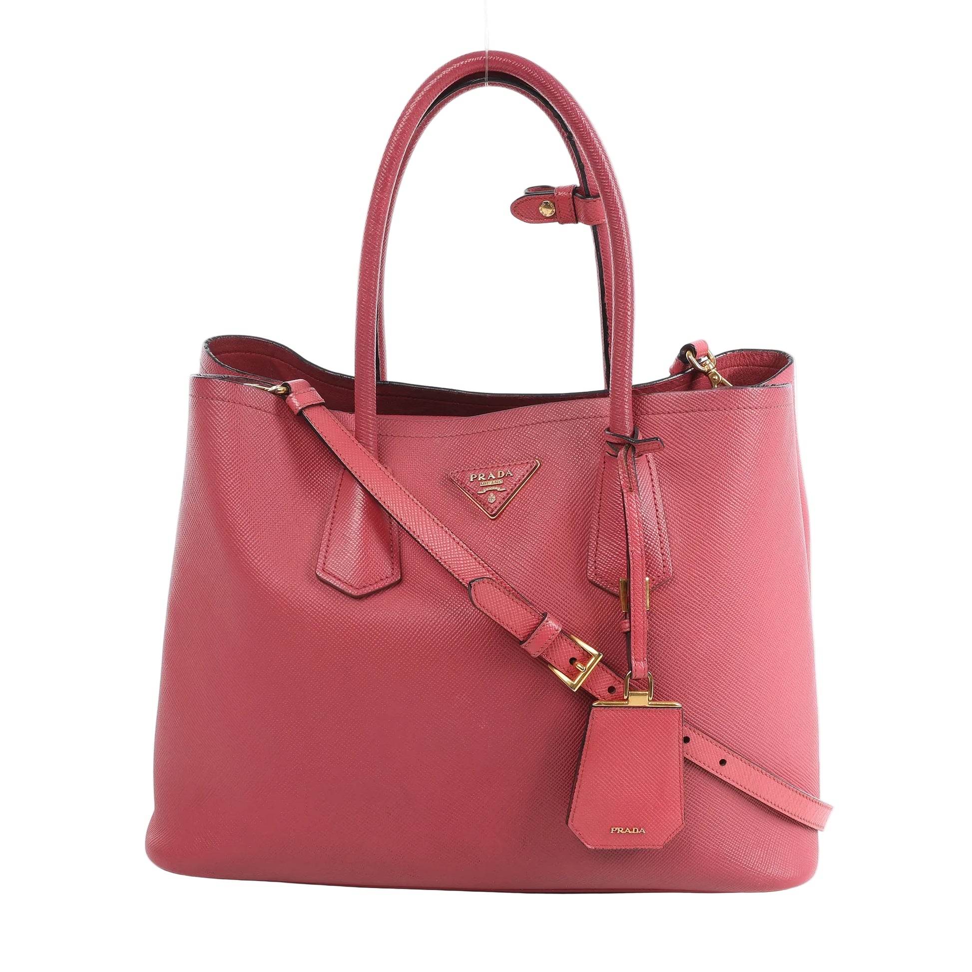Prada Cuir Saffiano Lux 2Way handbag in pink textured leather with gold-tone hardware, dual top handles, detachable crossbody strap, and leather ID tag.