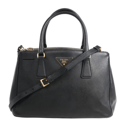 Prada Galleria Saffiano Lux Leather 2Way Handbag in black, featuring textured leather, gold-tone hardware, top handles, detachable shoulder strap, and signature Prada triangle logo plaque on the front.