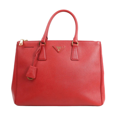 Front view of a Prada Galleria 2Way handbag in red Saffiano Lux leather featuring dual top handles, gold-tone hardware, a detachable key bell, and triangle Prada logo plaque.
