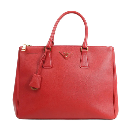 Front view of a Prada Galleria 2Way handbag in red Saffiano Lux leather featuring dual top handles, gold-tone hardware, a detachable key bell, and triangle Prada logo plaque.