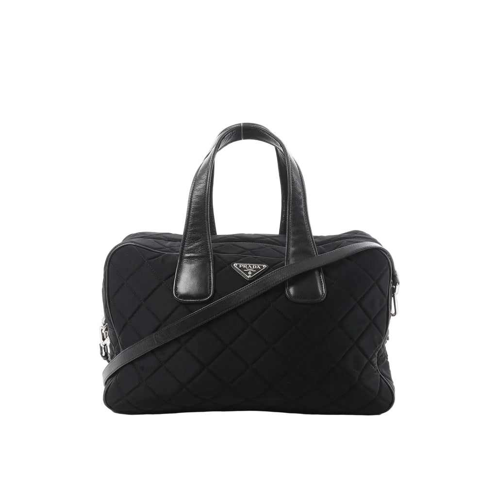 Prada black quilted nylon handbag with leather top handles, detachable shoulder strap, zip closure, and triangular Prada logo plaque on a white background.