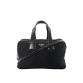 Prada black quilted nylon handbag with leather top handles, detachable shoulder strap, zip closure, and triangular Prada logo plaque on a white background.