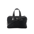 Prada black quilted nylon handbag with leather top handles, detachable shoulder strap, zip closure, and triangular Prada logo plaque on a white background.