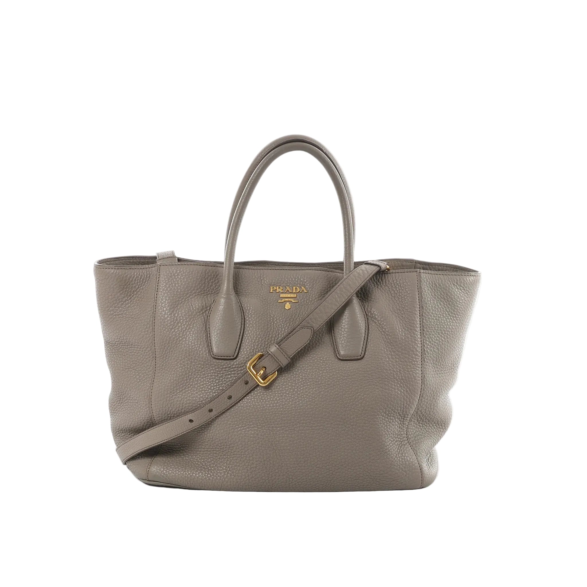 Prada Vitello Daino gray pebbled leather handbag with gold-tone Prada logo, top handles, and an adjustable shoulder strap on a white background.