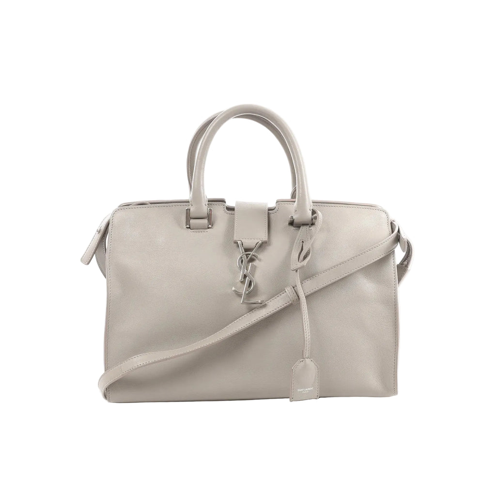 Gray Saint Laurent Baby Cabas leather handbag with double top handles, detachable shoulder strap, silver-tone YSL logo charm, and hanging leather clochette.