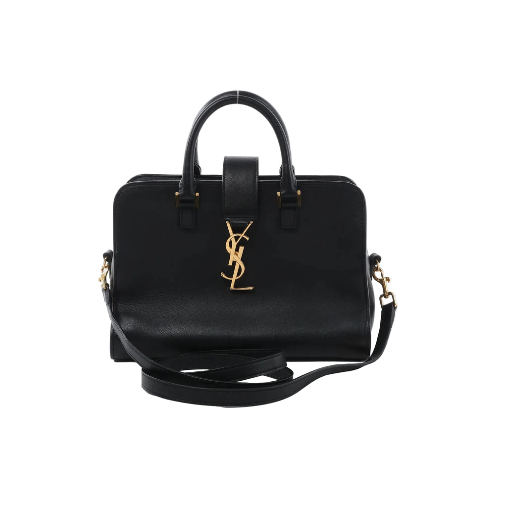 Saint Laurent Baby Cabas black leather handbag with top handles, detachable shoulder strap, and gold-tone YSL logo on the front, on a white background.