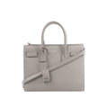 Gray Saint Laurent Baby Sac de Jour leather handbag with double top handles, detachable shoulder strap, embossed logo, and hanging leather clochette.