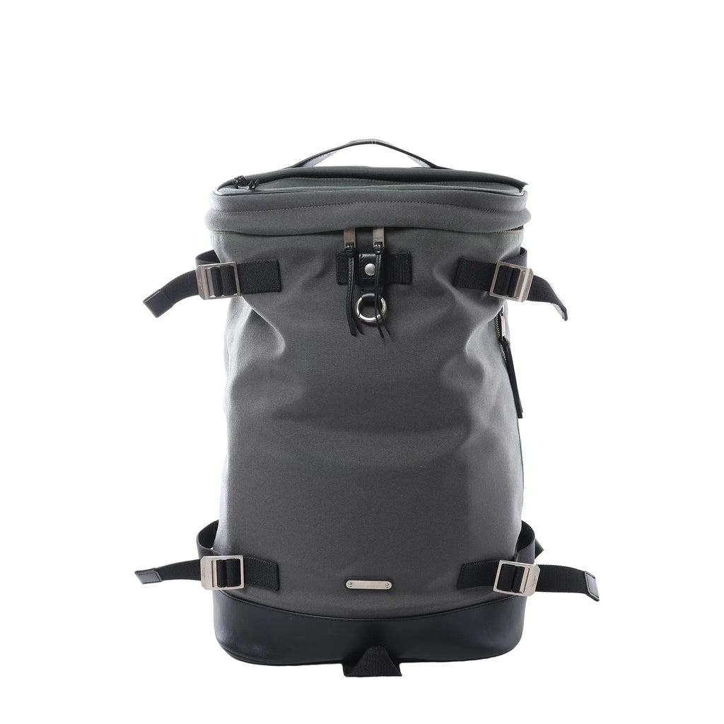 Saint Laurent Livington backpack in dark gray canvas with black leather base, adjustable webbing straps with metal buckles, top handle and front ring detail on white background.