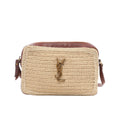Saint Laurent Paris Lou Camera crossbody bag in beige raffia with brown leather trim, adjustable leather shoulder strap, zip closure, and gold-tone YSL logo on a white background.