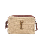 Saint Laurent Paris Lou Camera crossbody bag in beige raffia with brown leather trim, adjustable leather shoulder strap, zip closure, and gold-tone YSL logo on a white background.
